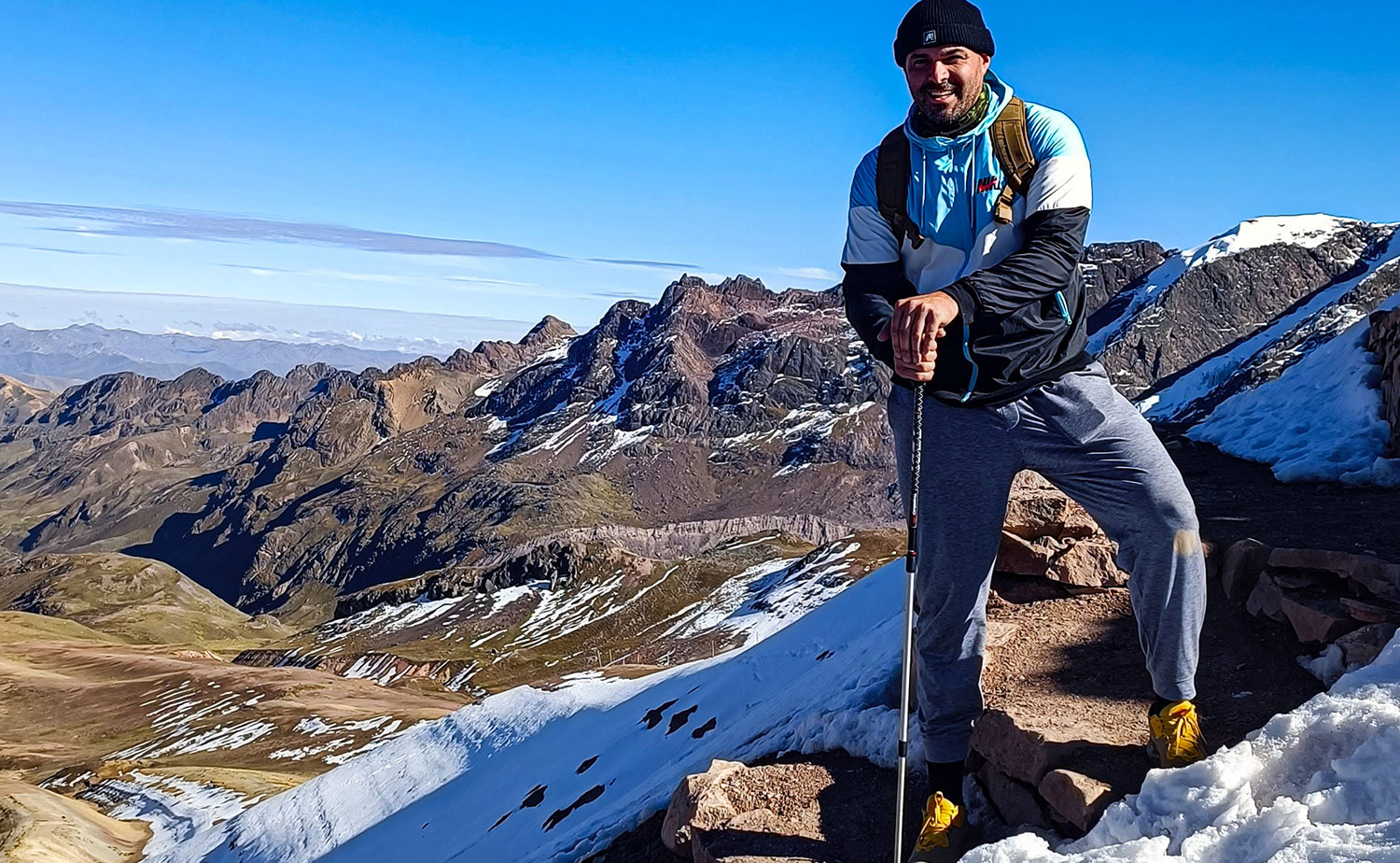 Hiker posing in a rocky trail leading toward Rainbow Mountain